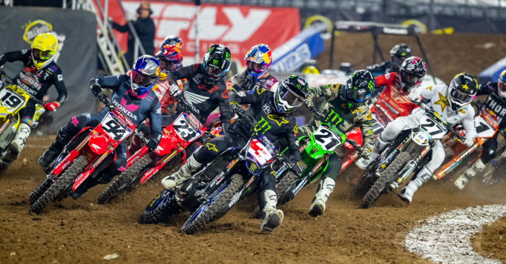 Reigning Monster Energy AMA Supercross Champion Eli Tomac (3) leading a star-studded field into the first turn at State Farm Stadium in Glendale, Ariz. Photo Credit: Feld Motor Sports