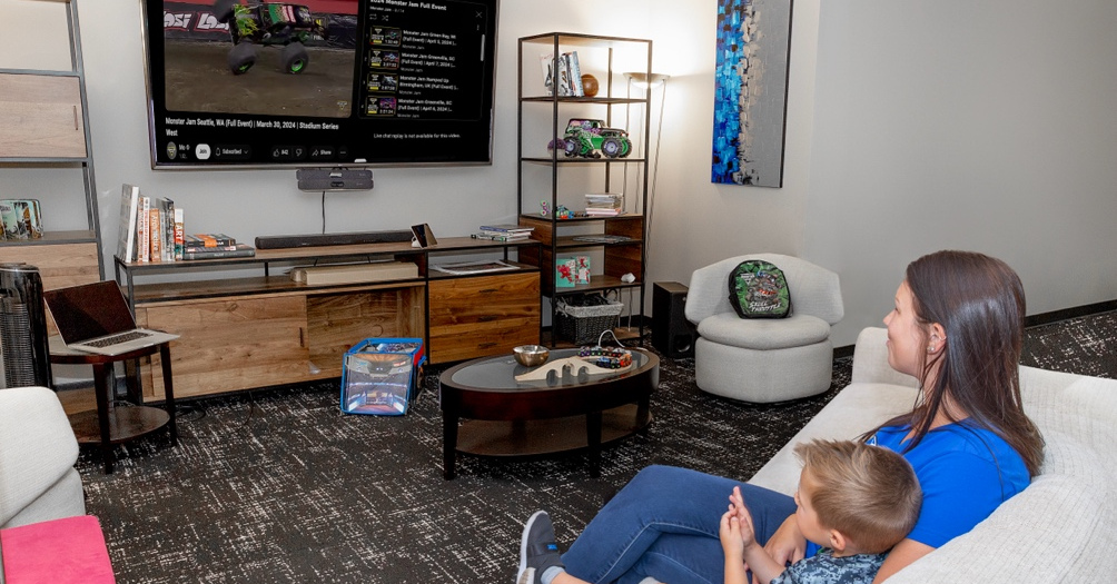 Woman and child watching Monster Jam live streaming on TV.